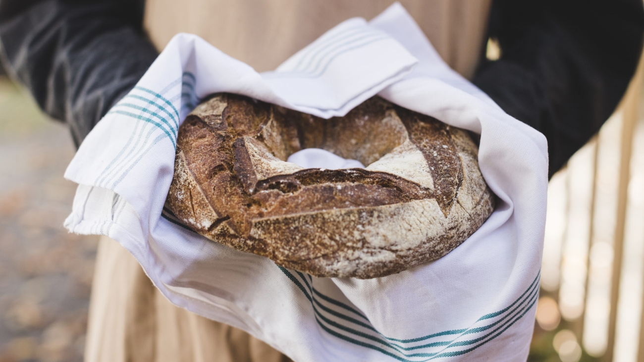 woman-s-hand-showing-rustic-bagel-bread-white-napkin
